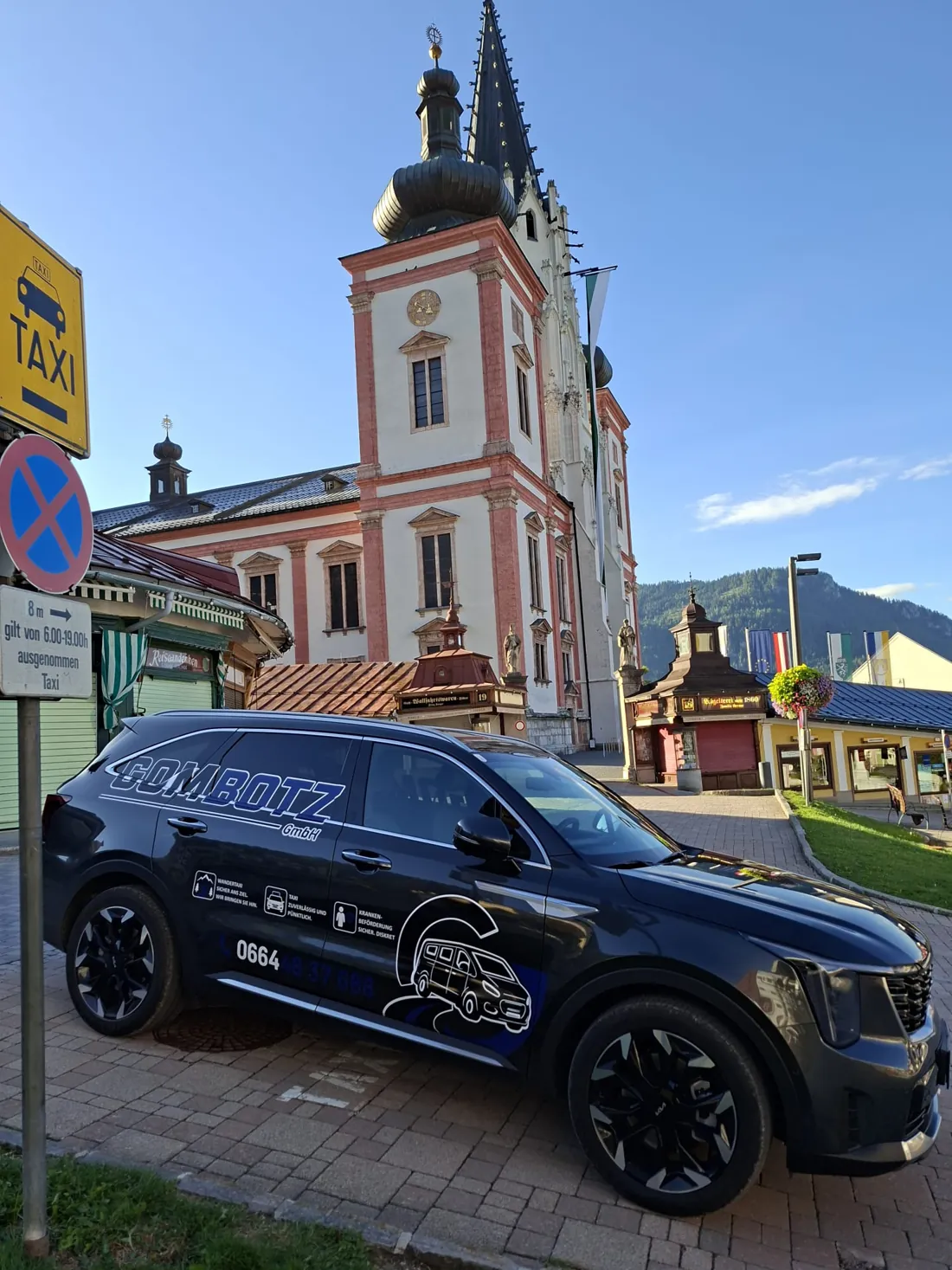 GOMBOTZ-Taxi, ein dunkler Kia Sorento mit Beklebung, am Taxistandplatz vor der Basilika Mariazell